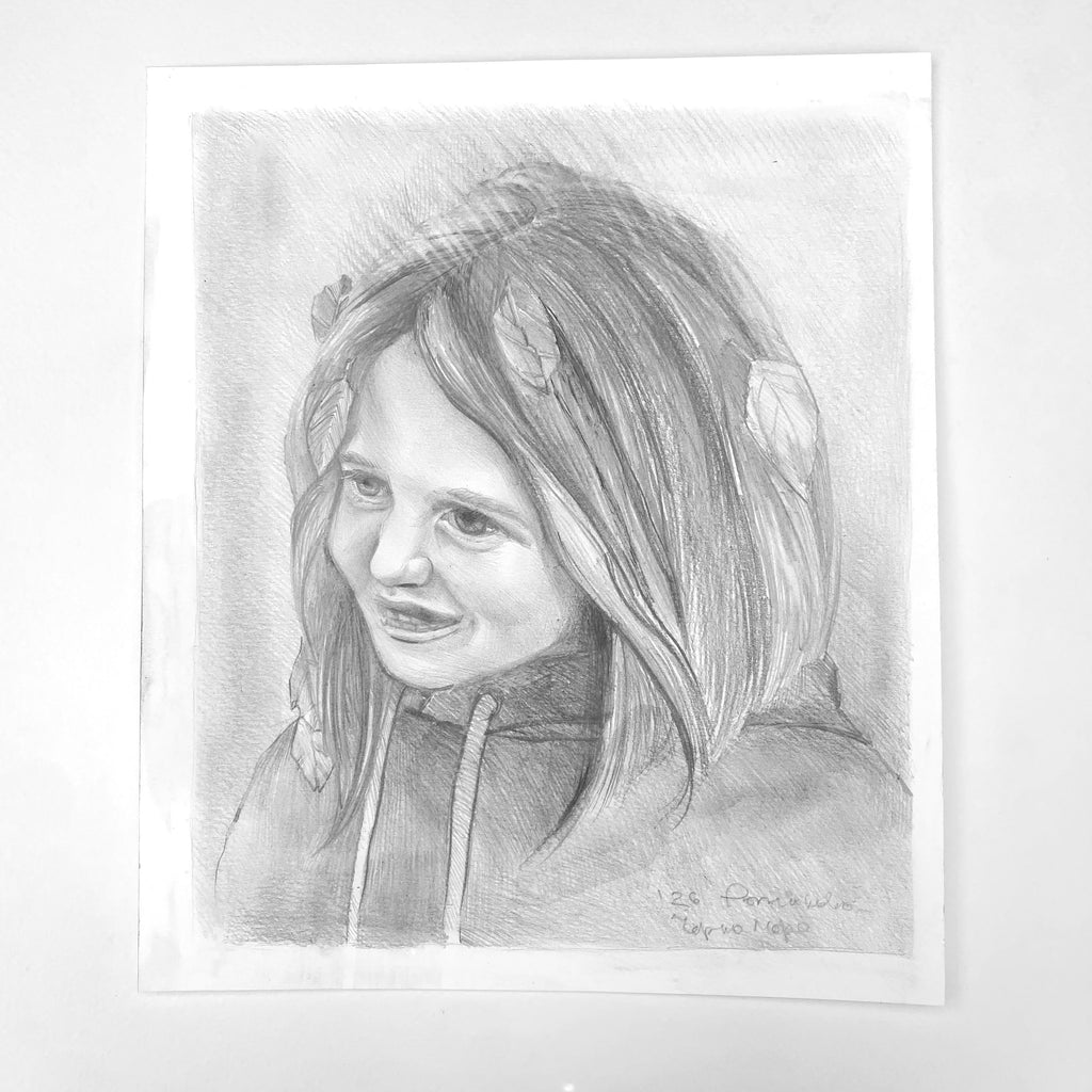 A black and white pencil sketch portrait of a young girl with a smile, presented on a white sheet of paper against a light gray background.