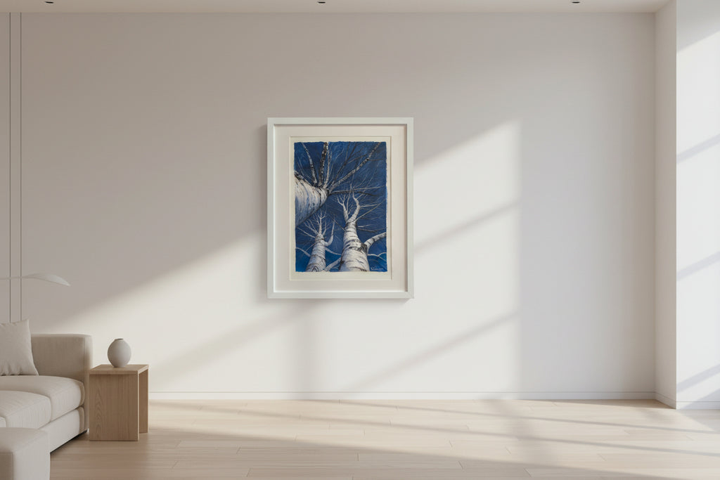 Framed artwork of birch trees against a blue sky with a white frame.