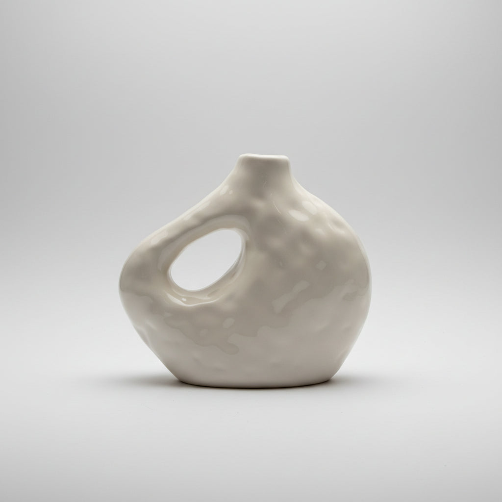 A glossy, organic-shaped ceramic vase with a large integrated loop handle, shown on a dark surface against a dark gray textured background.
