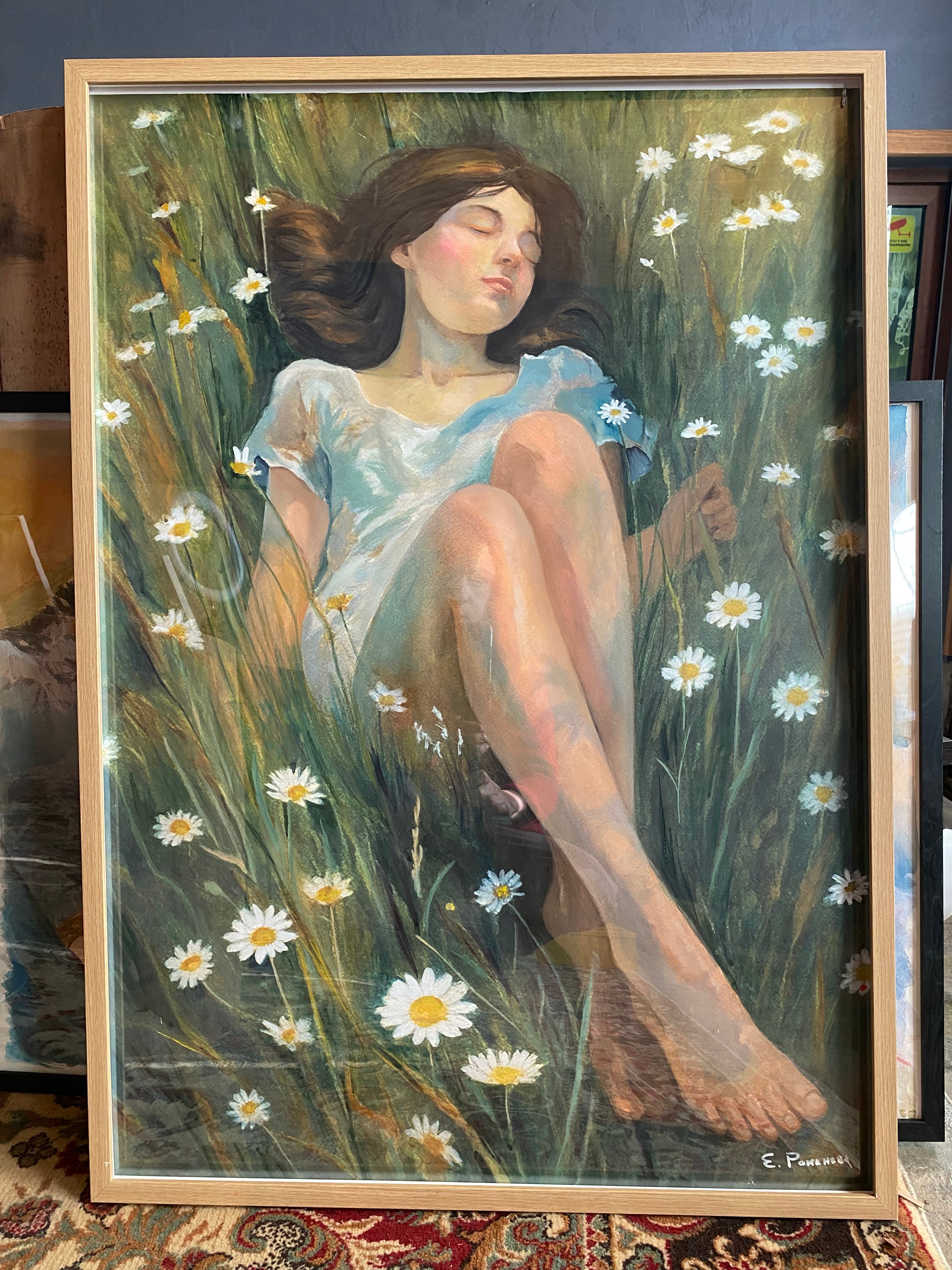 Painting of a woman lying on grass with flowers, framed in a wooden frame.