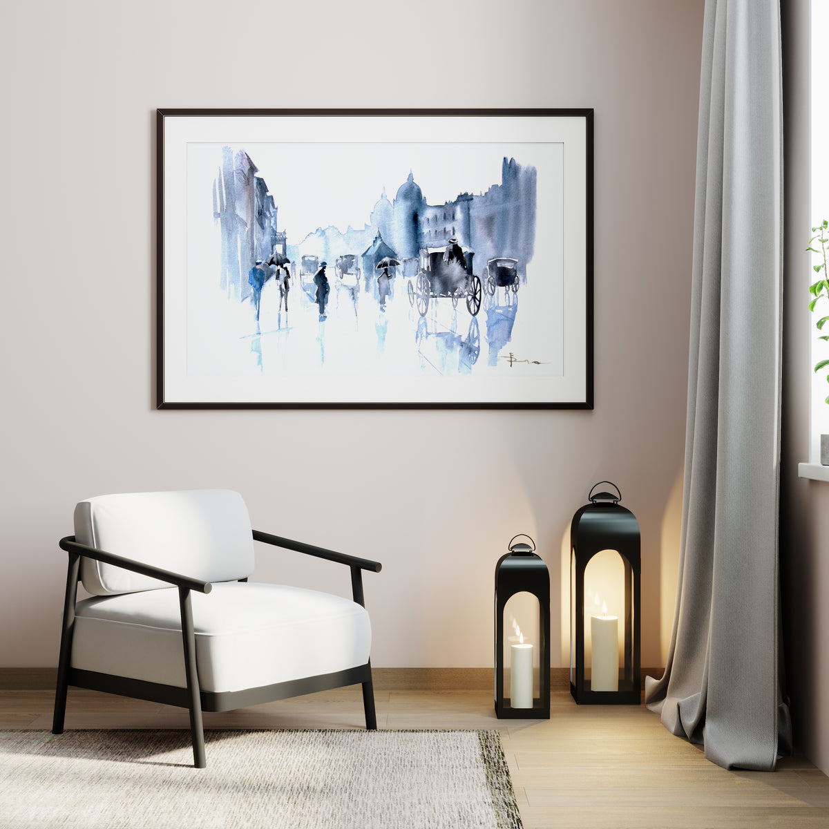 A framed abstract watercolor art print featuring blue and black brushstrokes on a white background, hung on a beige wall in a modern living room setting with a white armchair, two black lanterns, and a gray curtain.