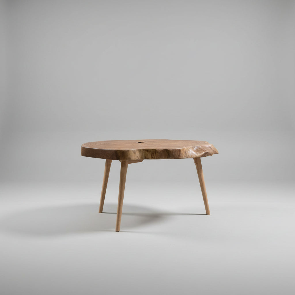 A rustic live-edge wooden coffee table with tapered legs, photographed in a workshop environment.